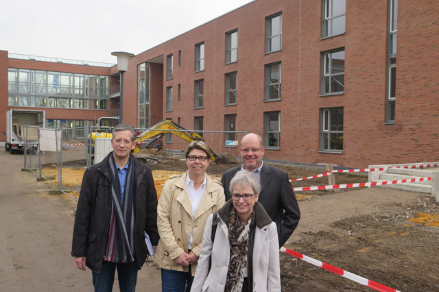 Thomas Brödenfeld, Beate Romanowski, Elke Landers, Theo Lemken (v.l.) laden die Bevölkerung zur Besichtigung des neuen Erweiterungsbaus für das Alten- und Pflegeheim „Haus Bossow“ ein. Das Foto zeigt rechts den Erweiterungsbau. Foto: Helmut Scheffler