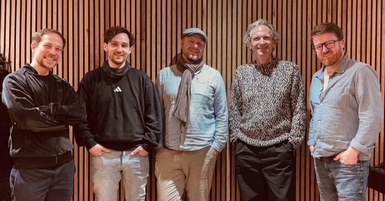 The Five Guys Quartett steht vor einer Holzwand und blickt in die Kamera