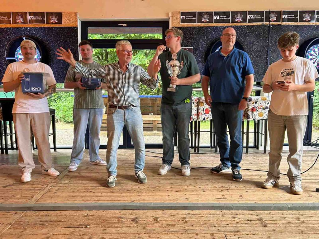 Lukas Klevermann gewinnt den ersten Volksbank-Steeldarts-Cup in Schermbeck und präsentiert den Siegerpokal in der Selecao-Halle.