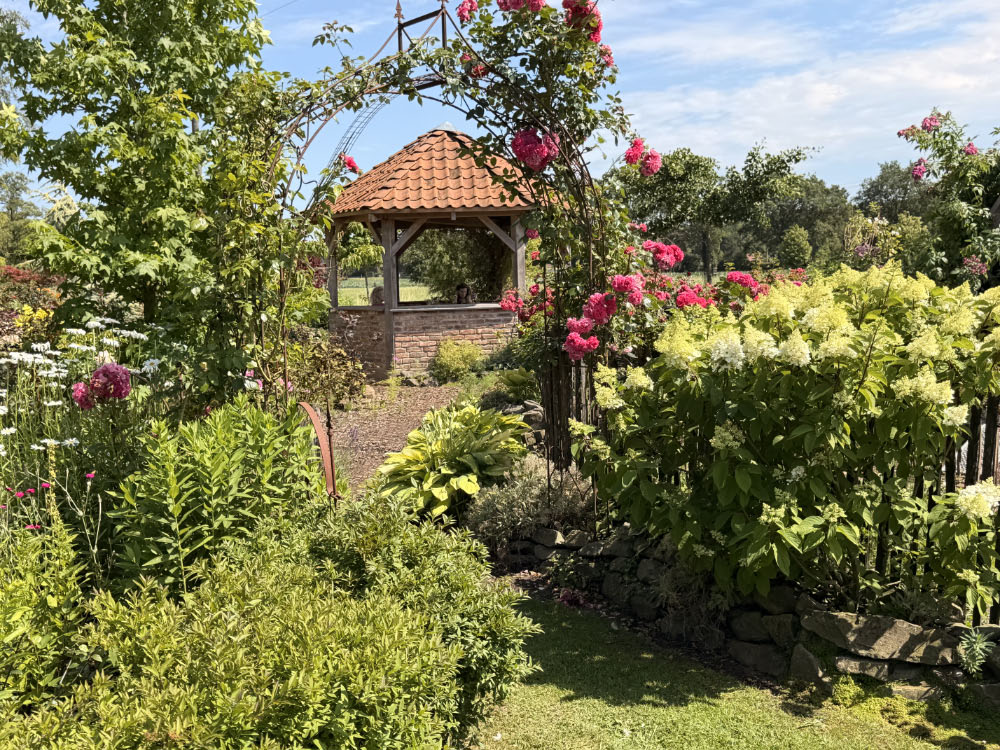 Bauerngarten von Michaela und Pascal Paus am Vossenbergweg in Schermbeck mit Stauden, Rosen, Naturstein-Hochbeeten und historischem Gutshof.